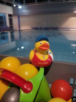 Hier siehst du eine gelbe DLRG-Ente vor einem leeren Schwimmbecken.